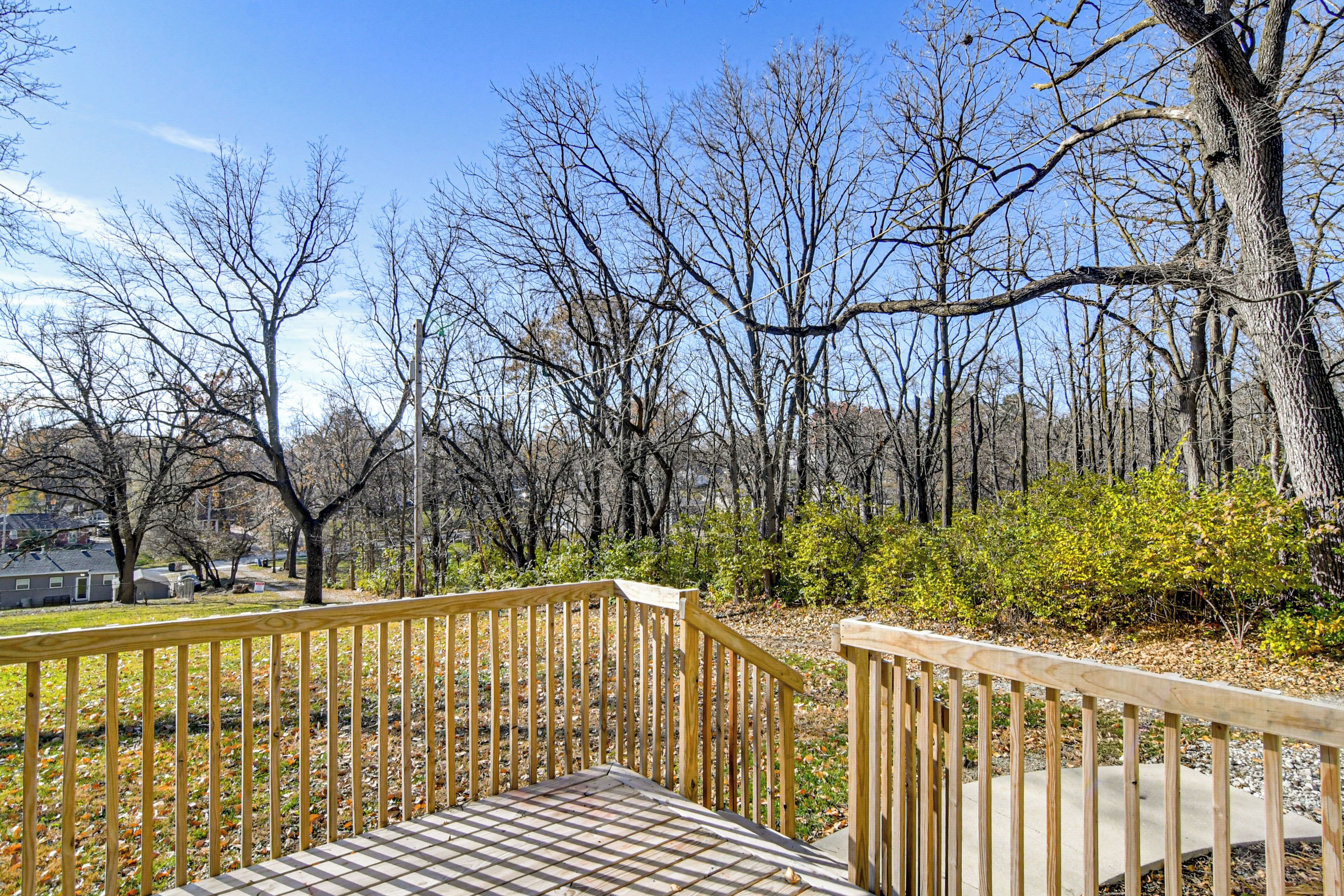 Une terrasse en bois avec un motif quadrillé, entourée d’arbres sans feuilles et sous un ciel dégagé.
