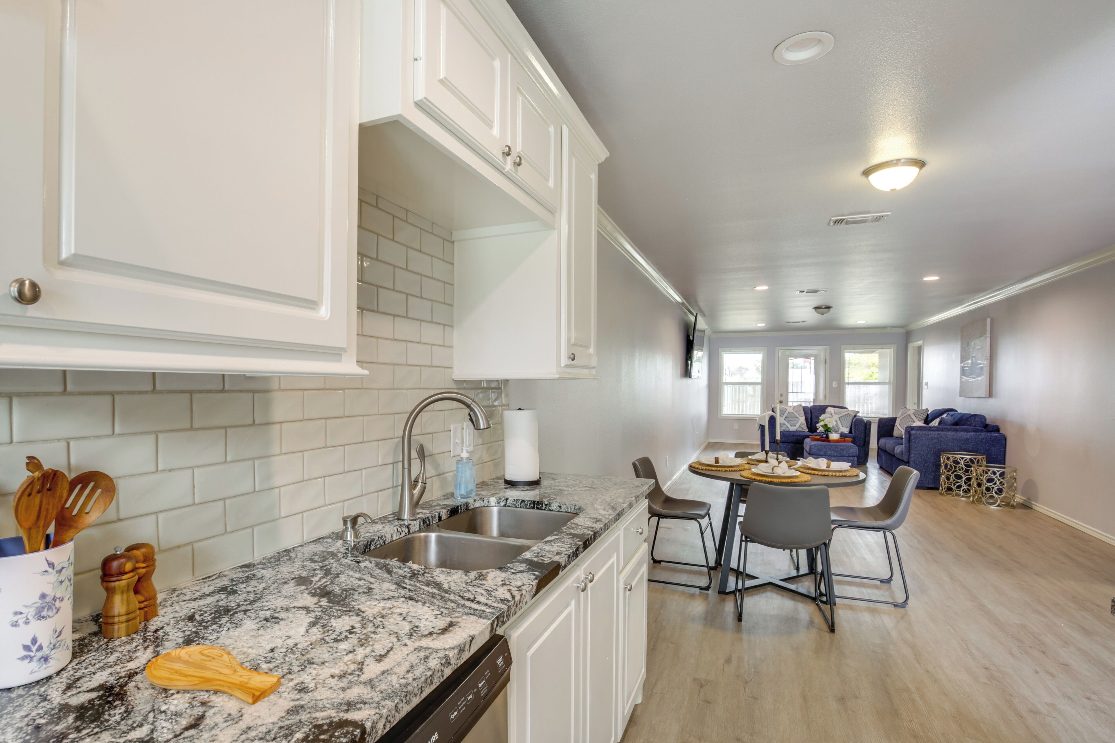 A kitchen with white cabinets, a granite countertop, and a dining area with a table and chairs.