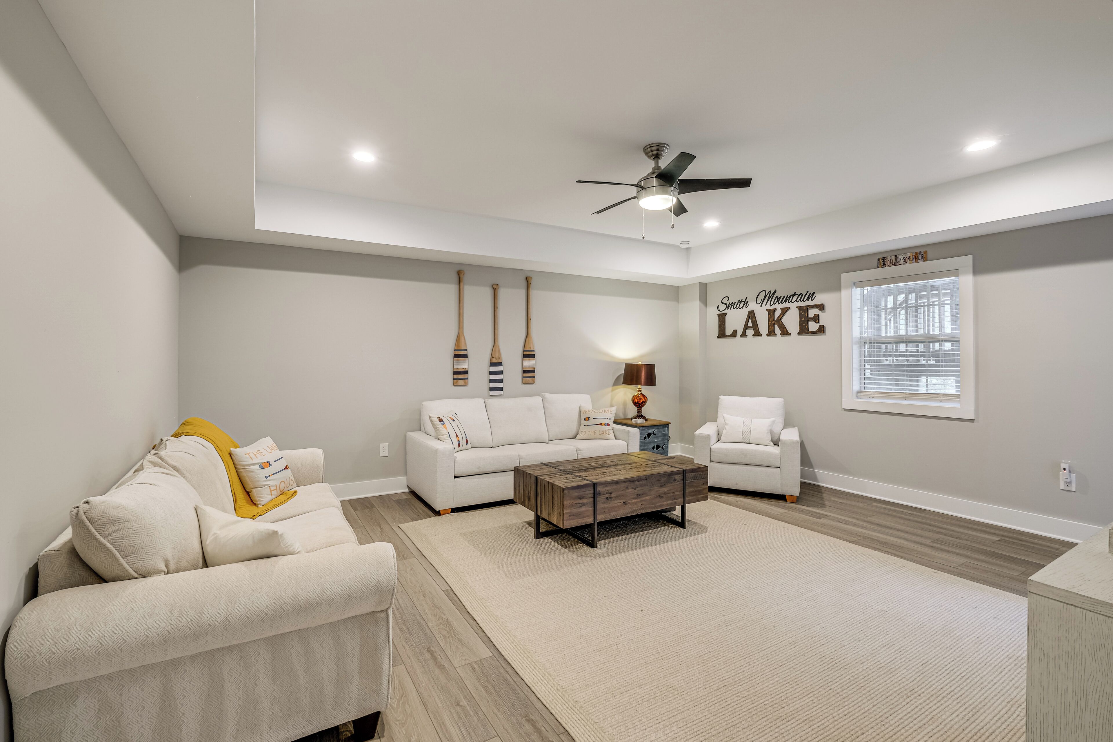 A modern living room with a white sofa, a wooden coffee table, and a ceiling fan.