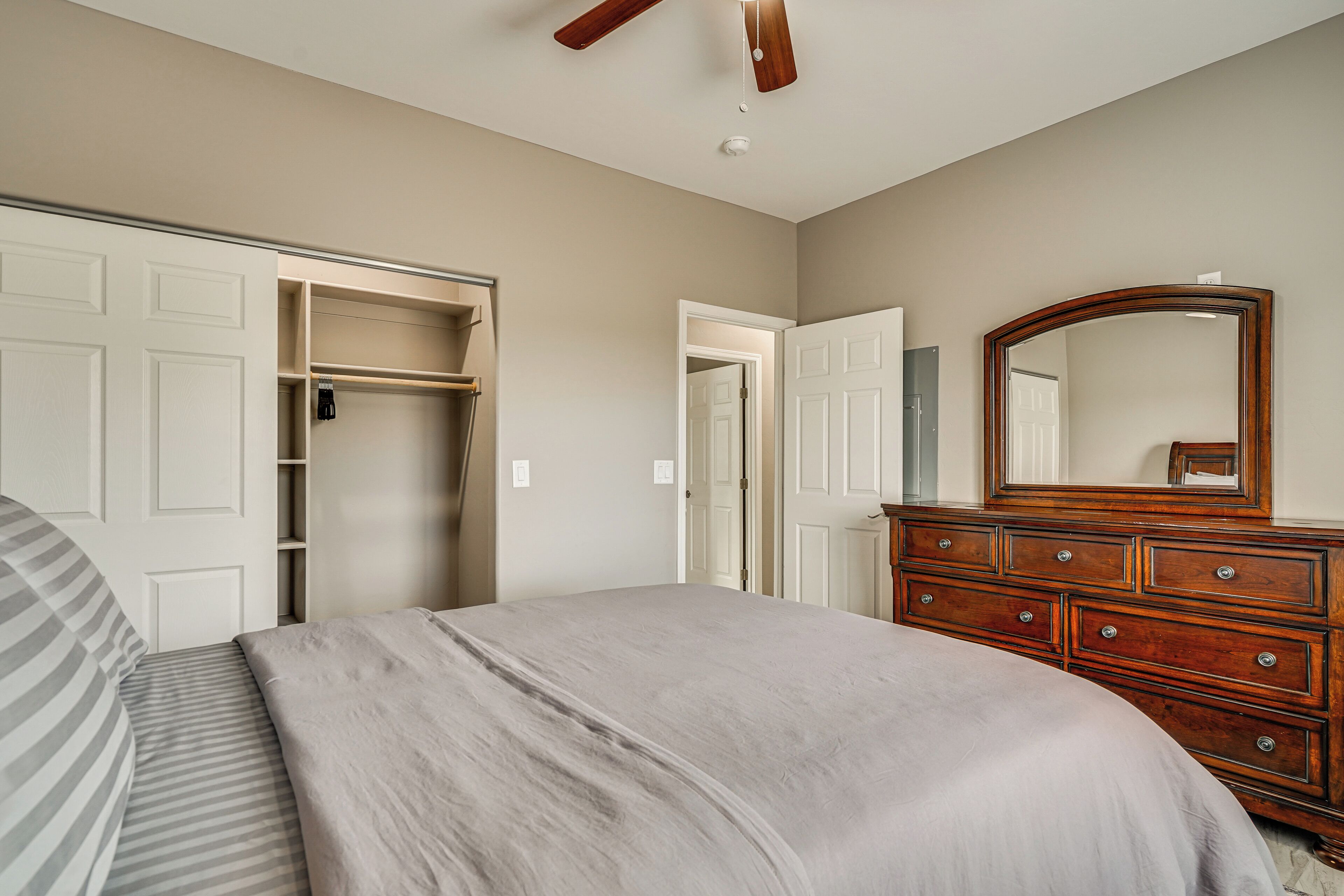 A bedroom with a bed, a dresser, a wardrobe, and a mirror.