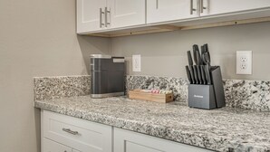 A kitchen with white cabinets, a granite countertop, a coffee maker, and a knife block. - Near Casino & Dtwn! Tucson Townhome: Saguaro NP (Tucson)