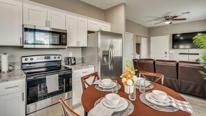 A modern kitchen with stainless steel appliances, a dining area with a brown table set for four, and a brown leather couch in the background. - Near Casino & Dtwn! Tucson Townhome: Saguaro NP (Tucson)