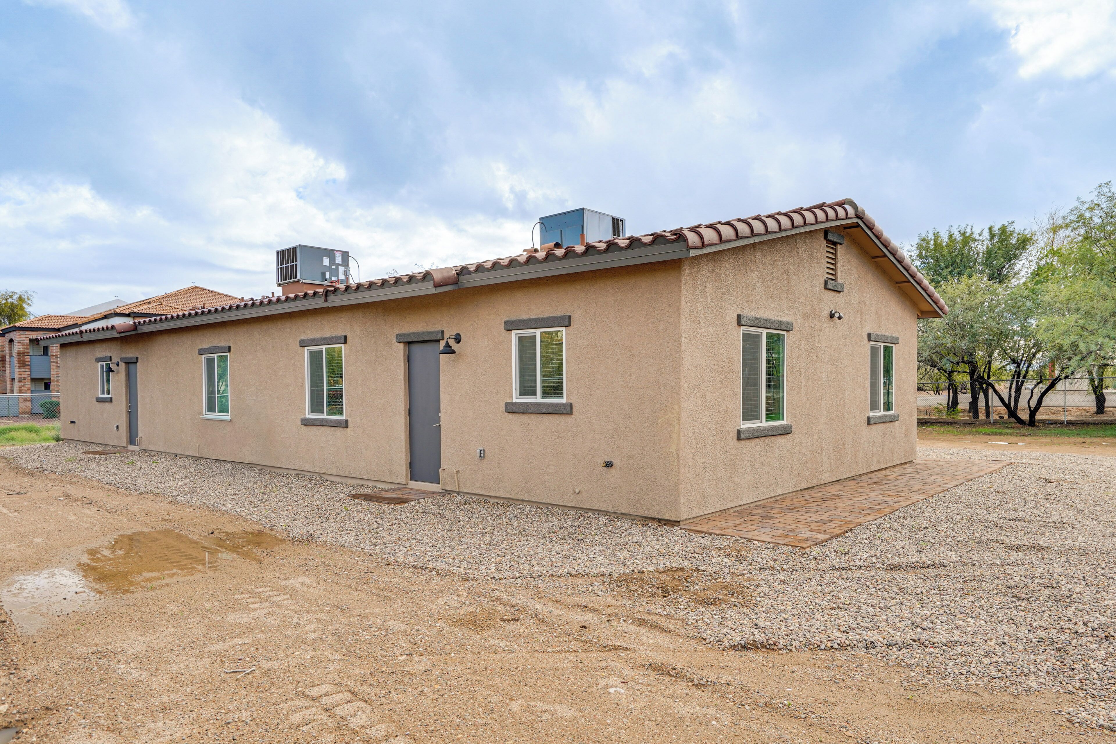 Une maison de plain-pied avec un toit plat, un petit porche et une allée gravillonnée.