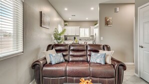 A living room with a brown leather sofa, a coffee table with flowers, and a kitchen in the background. - Near Casino & Dtwn! Tucson Townhome: Saguaro NP (Tucson)