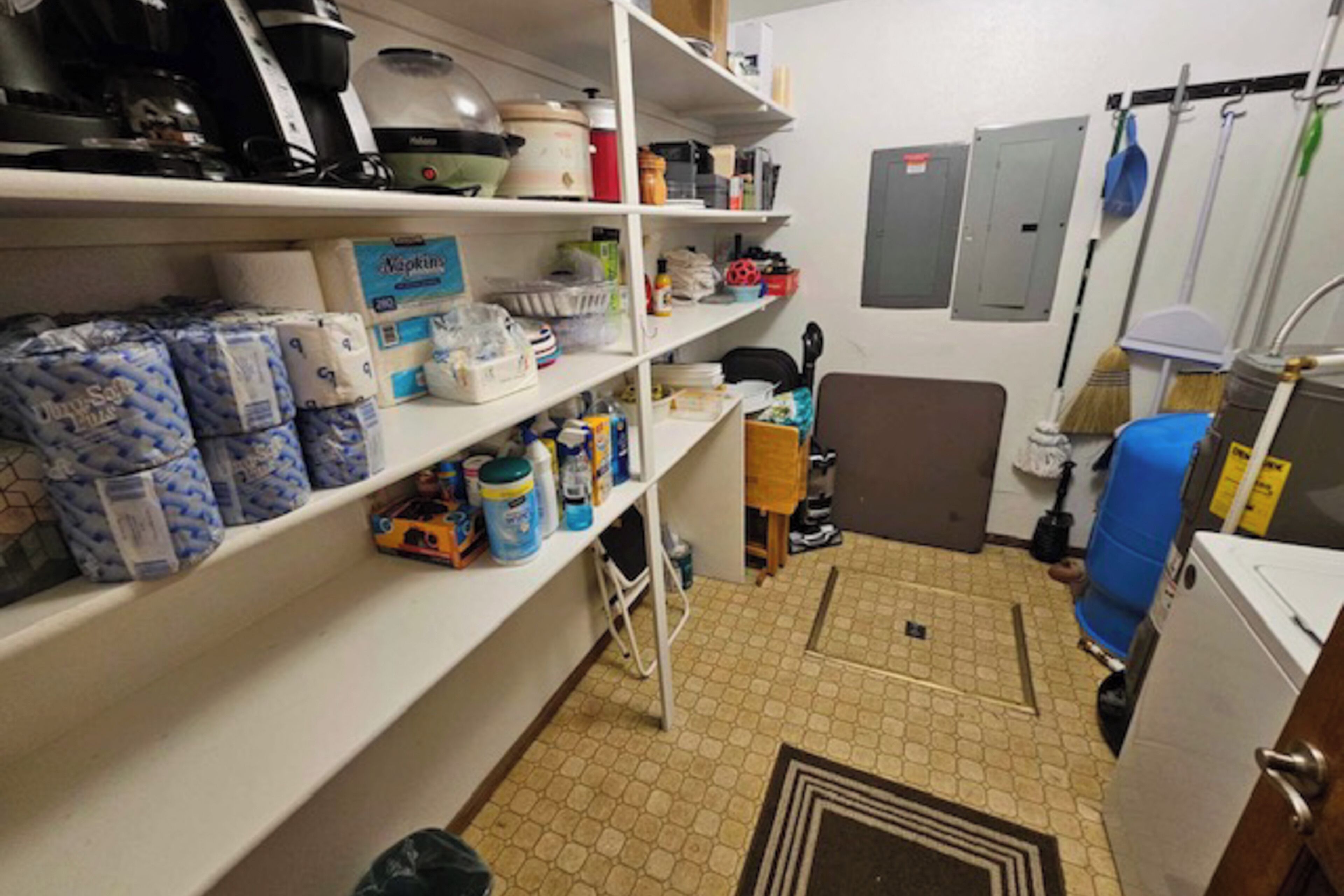 A compact kitchen with white shelves stocked with various items, a coffee maker, and a microwave.
