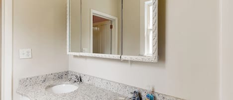 A bathroom with two sinks, a large mirror, and a door leading to another room.