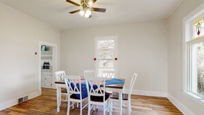 A dining area with a wooden floor, white chairs, a table with a blue tablecloth, and a ceiling fan. - 2BR Home w/ Mountain View, W & D, Private Yard (Ashton)