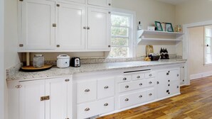 A kitchen with white cabinets, a granite countertop, and a window providing natural light. - 2BR Home w/ Mountain View, W & D, Private Yard (Ashton)