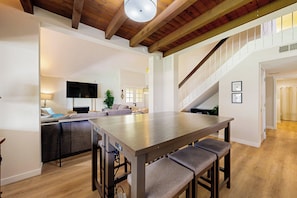 A spacious kitchen with a large island, wooden beams on the ceiling, and a staircase leading to an upper level. - 4BR Dog-friendly Home w/ Pool, Spa, Grill & A/C (Mission Viejo)