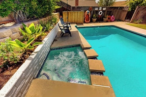 A swimming pool with a hot tub section, surrounded by a wooden fence, and a chair near the edge. - 4BR Dog-friendly Home w/ Pool, Spa, Grill & A/C (Mission Viejo)