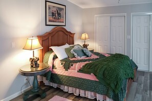 A bedroom with a wooden headboard, two bedside lamps, a green blanket, and a framed picture on the wall. - Countryside 3BR on 1 Protected Acre w/ Grill (Sanford)