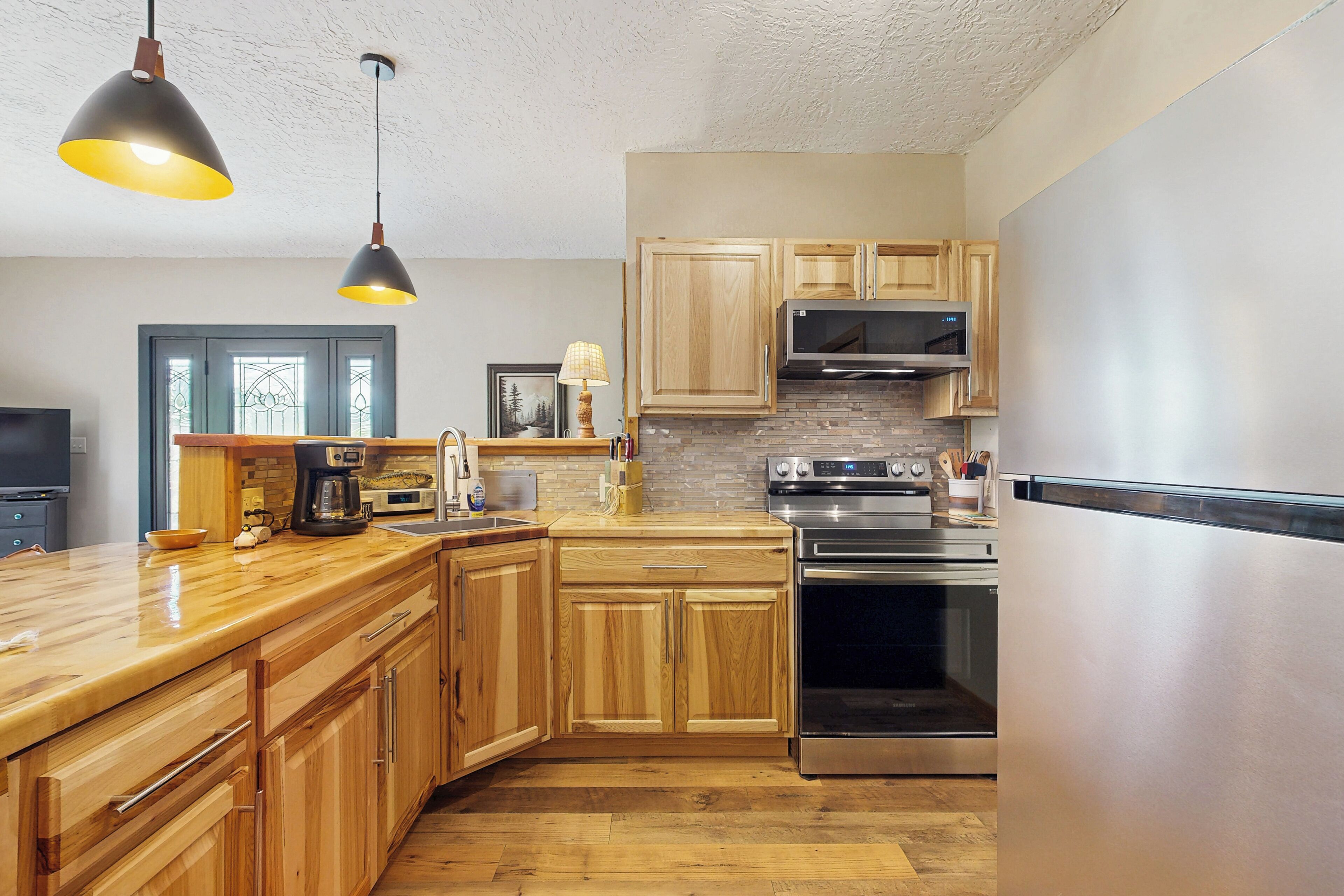 A kitchen with wooden cabinets, a stainless steel refrigerator, and a built-in oven.