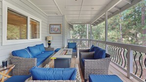 Eine überdachte Veranda mit Korbmöbeln, einem Tisch und einem Deckenventilator.