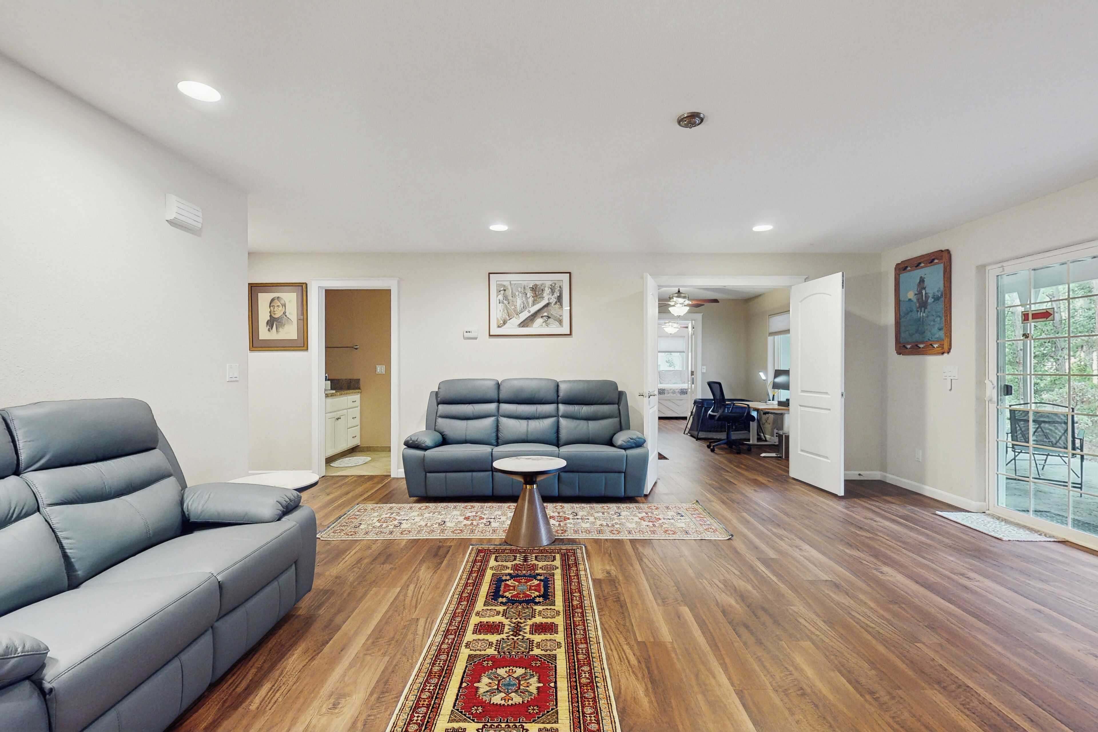 A living room with a grey sofa, a blue sofa, a coffee table, and a patterned rug.