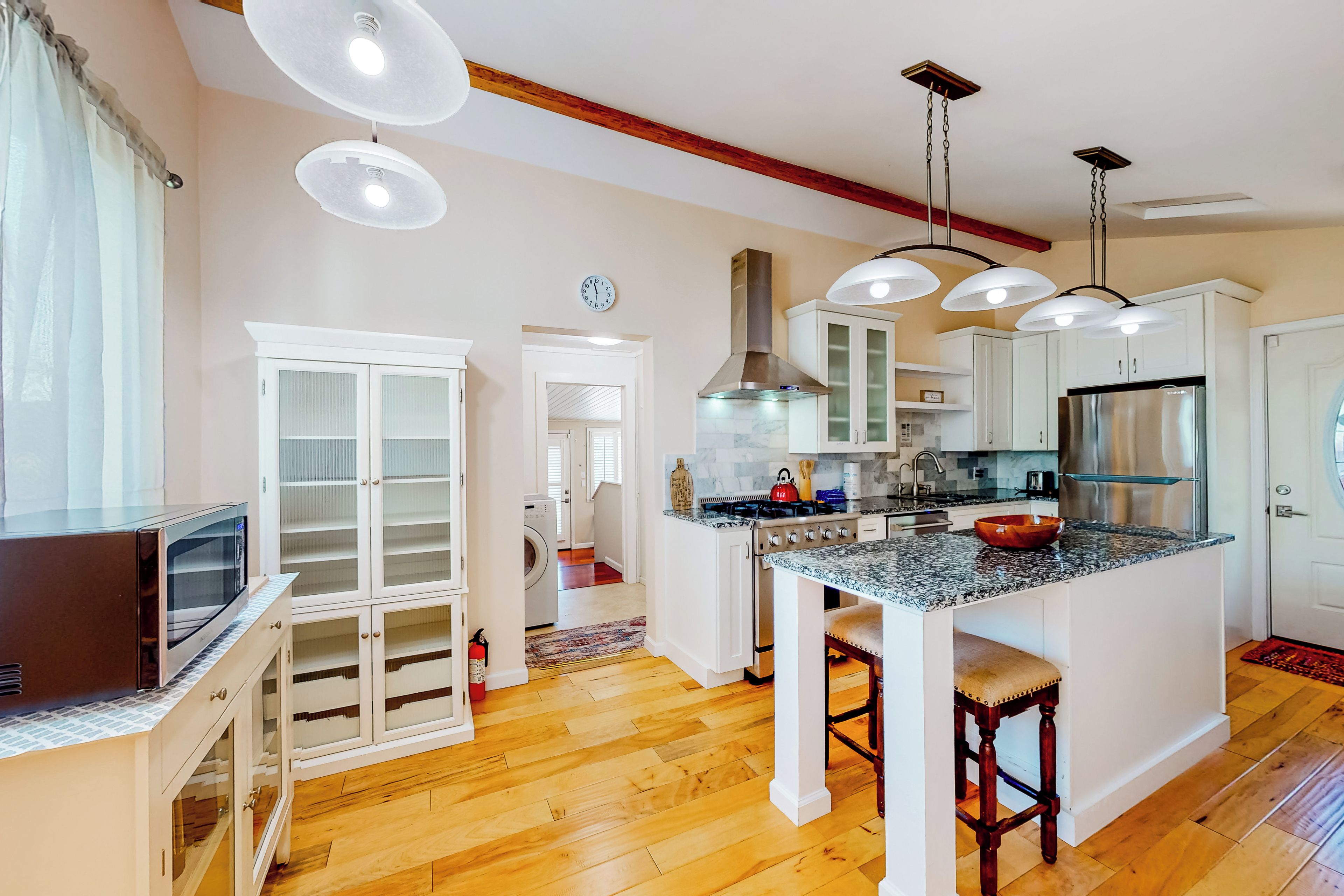 A modern kitchen with white cabinets, a stainless steel refrigerator, and a granite countertop island.