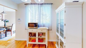 A kitchen with a microwave on a small table, a cabinet with glass doors, and a window with sheer curtains. - Centrally Located! Dog-friendly San Rafael Home (San Rafael)