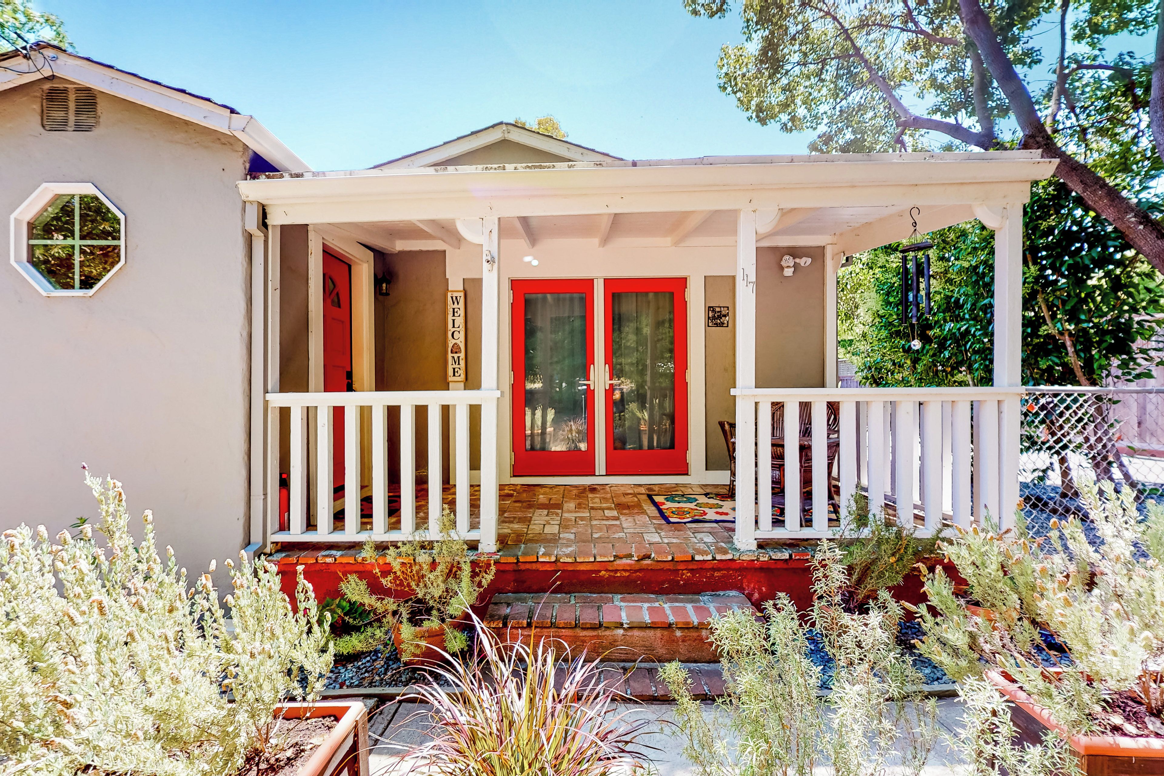 A house with a red door, white porch, and a welcome sign.