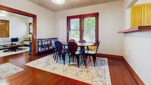 A dining area with a wooden table and chairs, a rug, and a bookshelf. - Walkable 1900s Home w/ Porch in Downtown Buda (Buda)