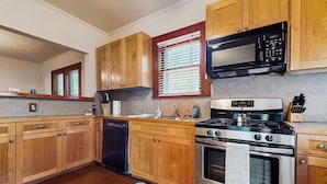 A kitchen with wooden cabinets, a stainless steel stove, a microwave, and a dishwasher. - Walkable 1900s Home w/ Porch in Downtown Buda (Buda)