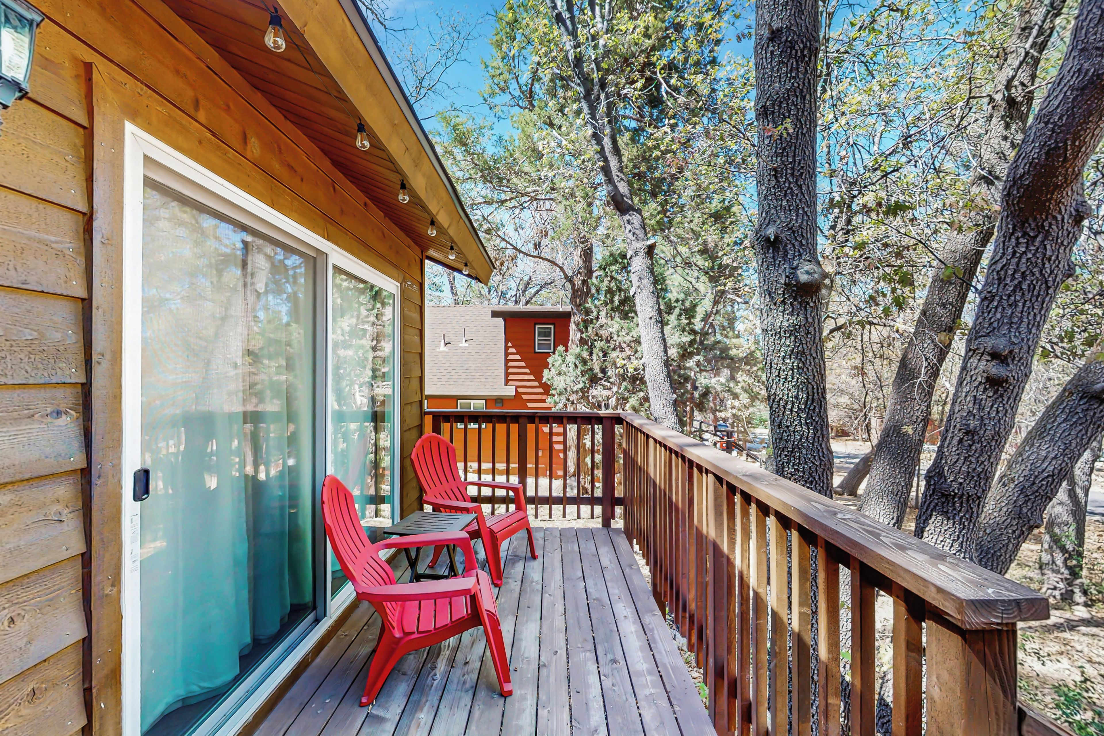 A wooden deck with red chairs and a glass door.
