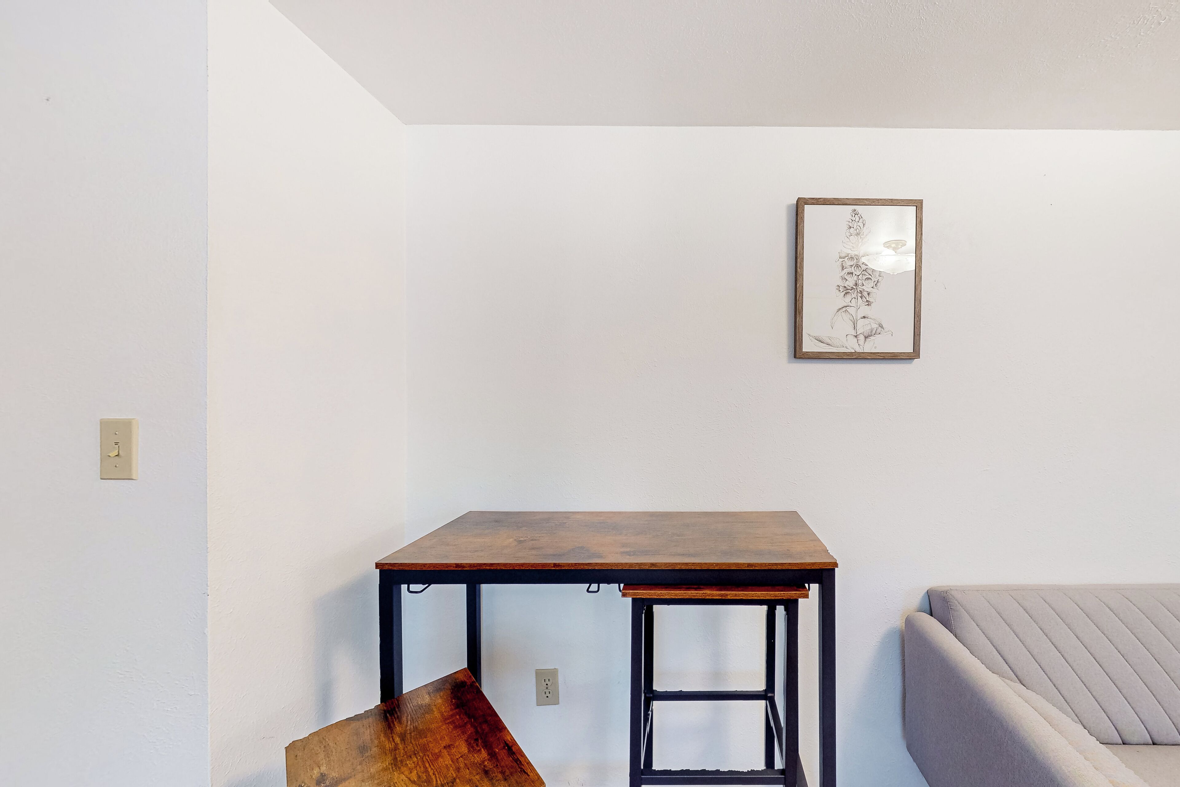 Una habitación con una mesa de madera, un sofá y una obra de arte enmarcada en la pared.