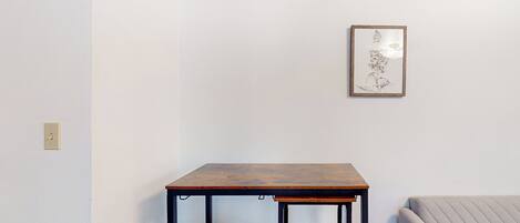 Una habitación con una mesa de madera, un sofá y una obra de arte enmarcada en la pared.