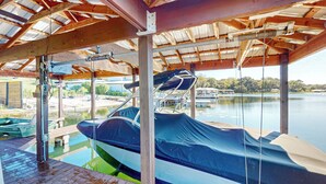 A covered boat dock with a covered area, wooden deck, and a view of a lake. - Escape the Heat! Lakefront Paradise in Mount Dora (Mount Dora)