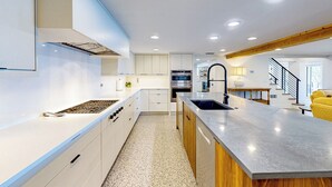 A modern kitchen with white cabinets, a stainless steel sink, and a central island. - Escape the Heat! Lakefront Paradise in Mount Dora (Mount Dora)