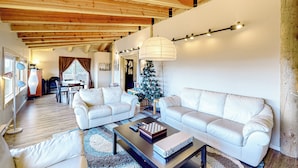 Un salón espacioso con dos sofás de cuero blanco, una mesa de centro y un árbol de Navidad.