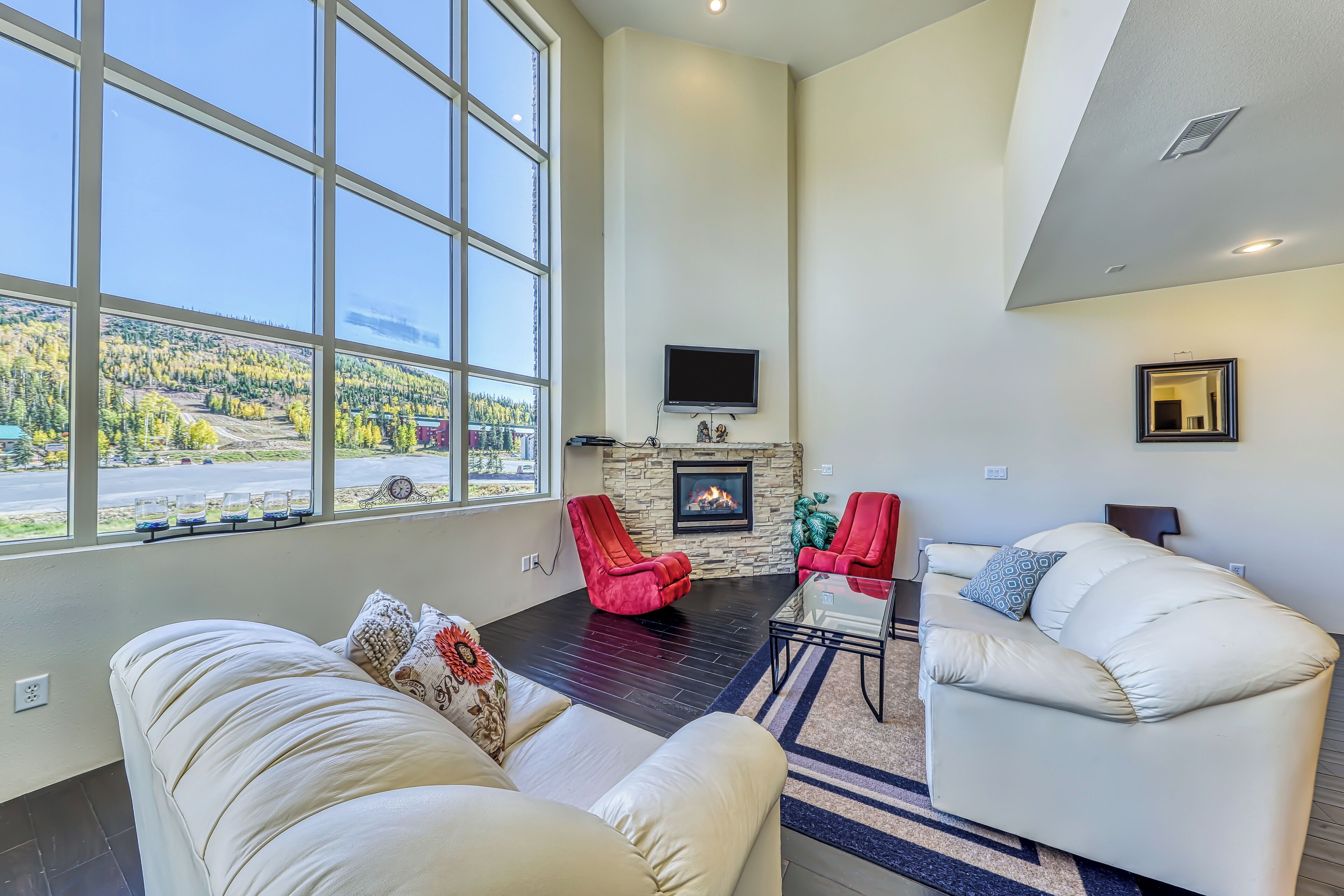 A spacious living room with a fireplace, large windows, and a cozy seating area.