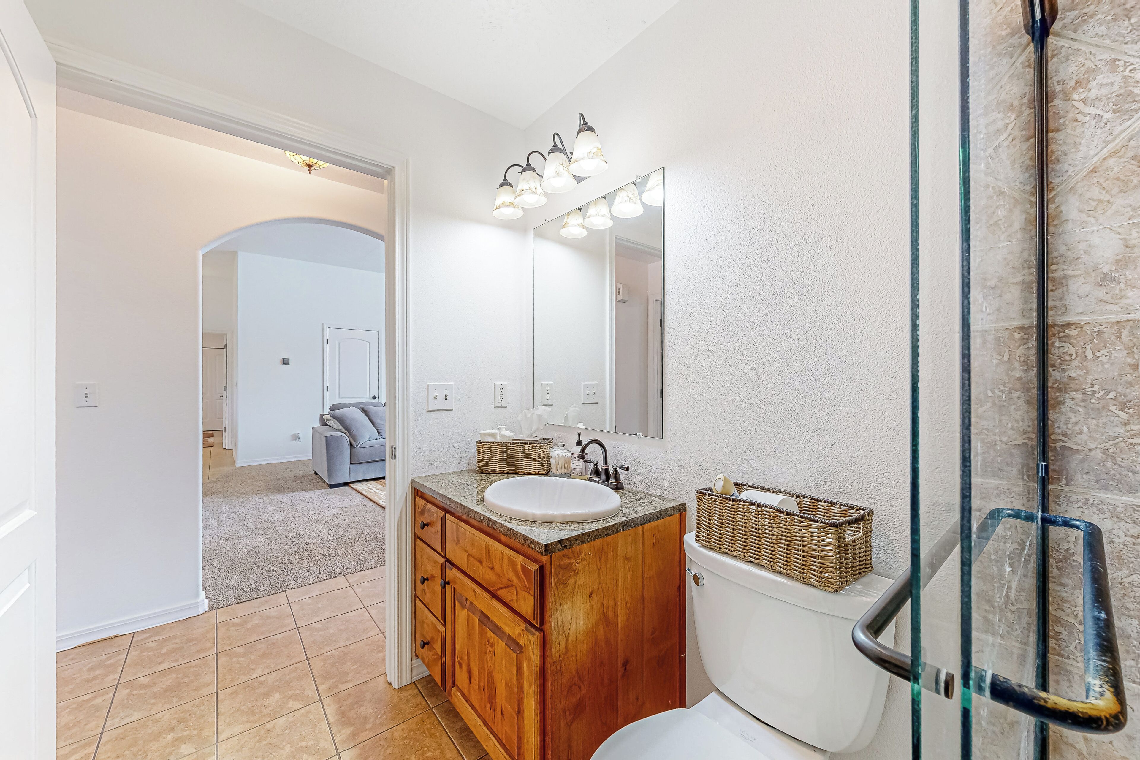 Un baño con tocador de madera, lavabo blanco y cabina de ducha de cristal.