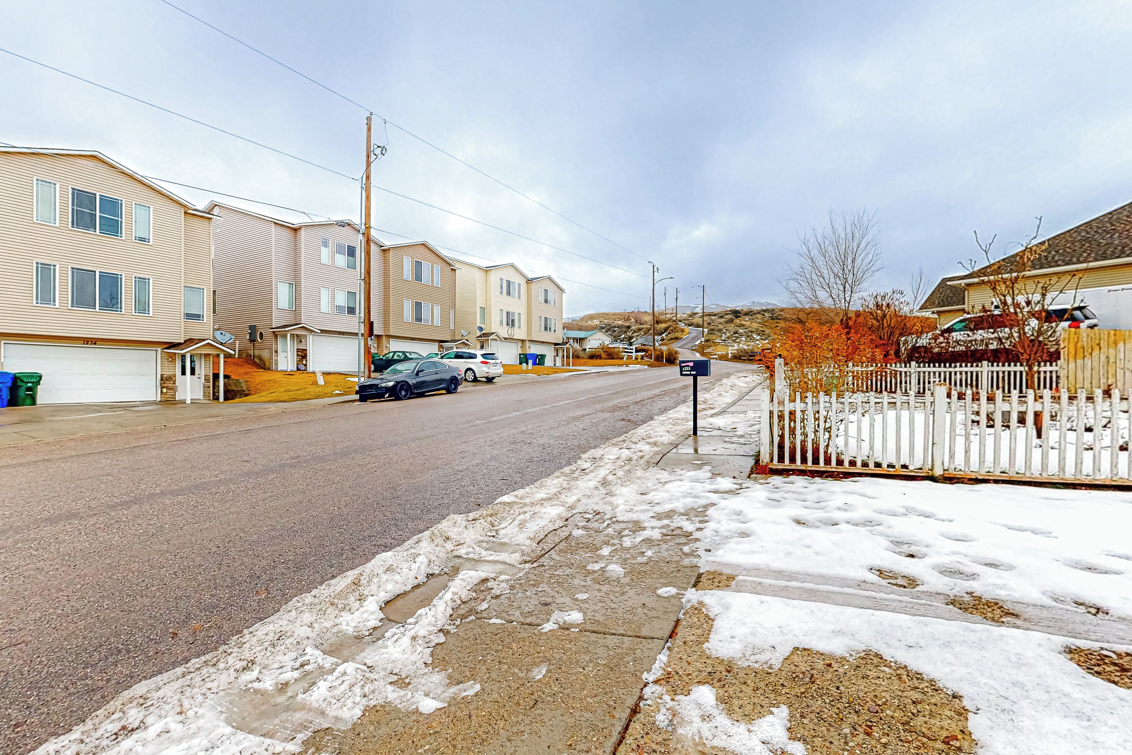 Une rue résidentielle bordée de maisons, avec un trottoir et un sol recouvert de neige.