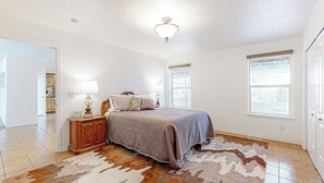 A bedroom with a bed, nightstand, lamp, and a cowhide rug. - 3BR Mountain View Home w/ Patio & Streaming (Pocatello)
