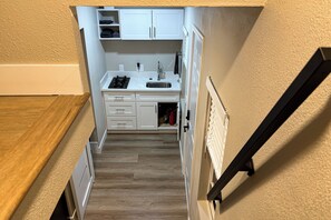 A compact kitchen with white cabinets, a sink, and a stove. - Pool & Hot Tub Access: Cozy Perris Tiny Home (Perris)