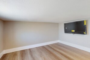 A room with a wooden floor, white walls, and a mounted flat-screen TV. - Pool & Hot Tub Access: Cozy Perris Tiny Home (Perris)