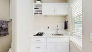 A compact bathroom with a white sink, a toilet, and a window with blinds. - Pool & Hot Tub Access: Cozy Perris Tiny Home (Perris)