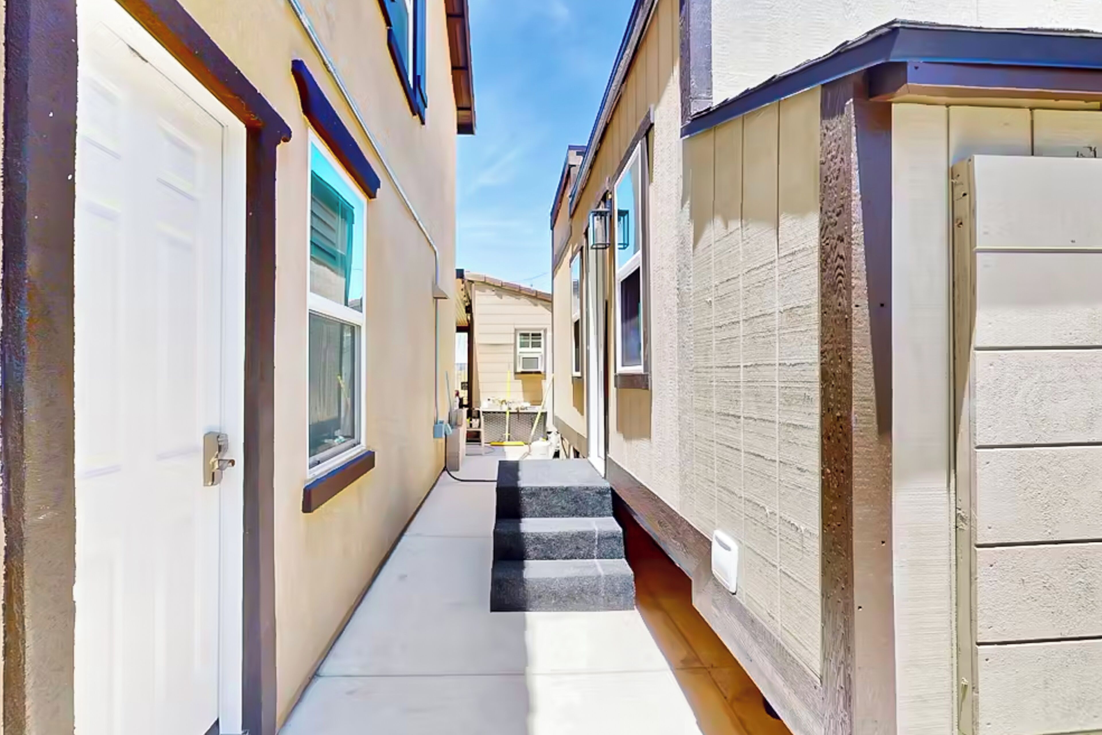 A narrow alleyway between two buildings with a set of concrete steps leading up to a door.