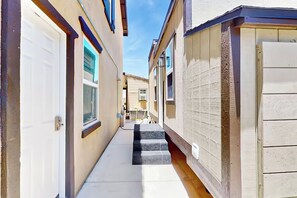 Um beco estreito entre dois edifícios, com um conjunto de degraus de concreto que levam a uma porta.