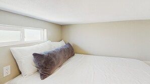 A bedroom with a bed, two pillows, a window, and a wall socket. - Pool & Hot Tub Access: Cozy Perris Tiny Home (Perris)