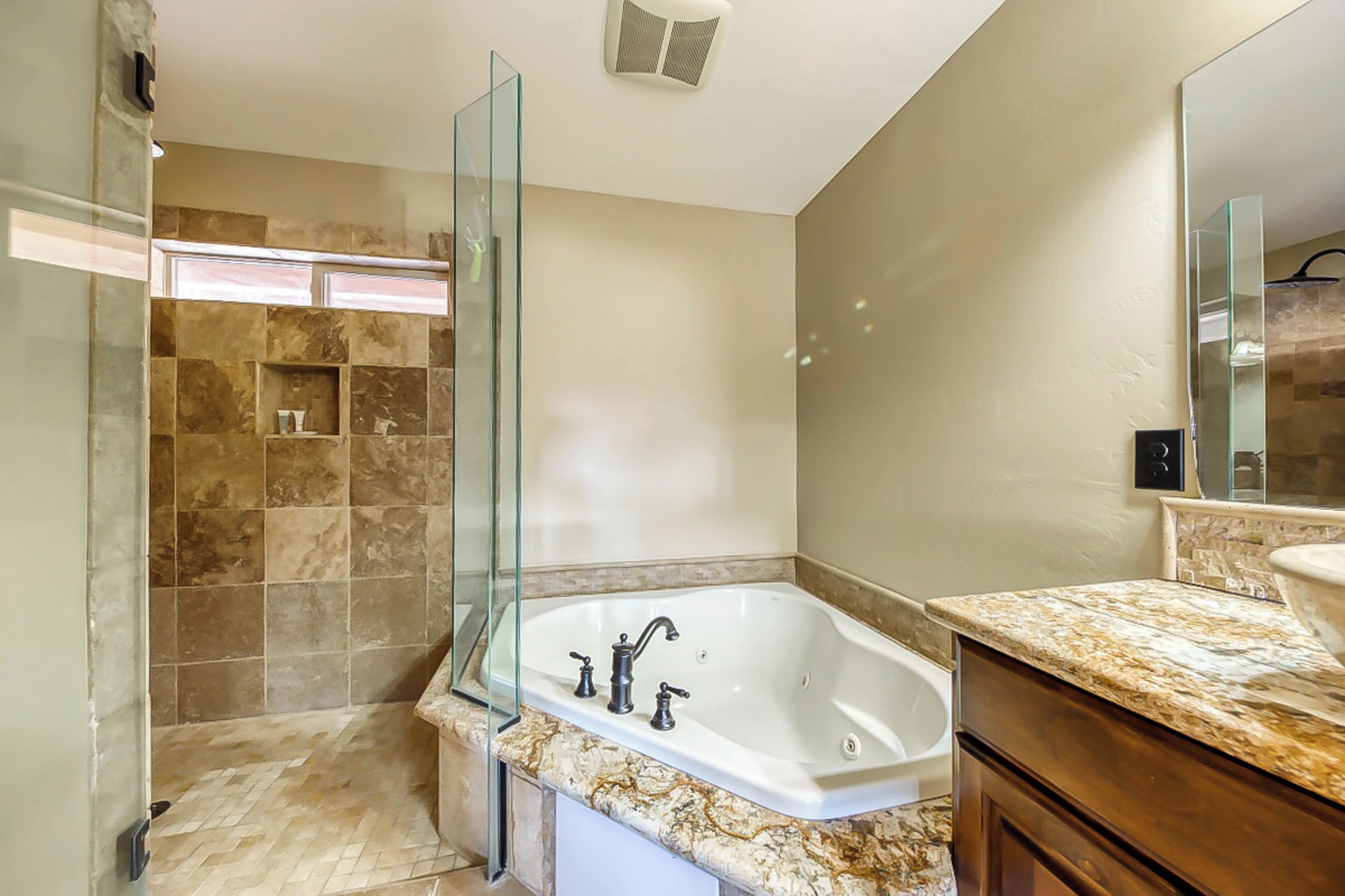 A modern bathroom with a freestanding bathtub, a glass shower enclosure, and a marble countertop.