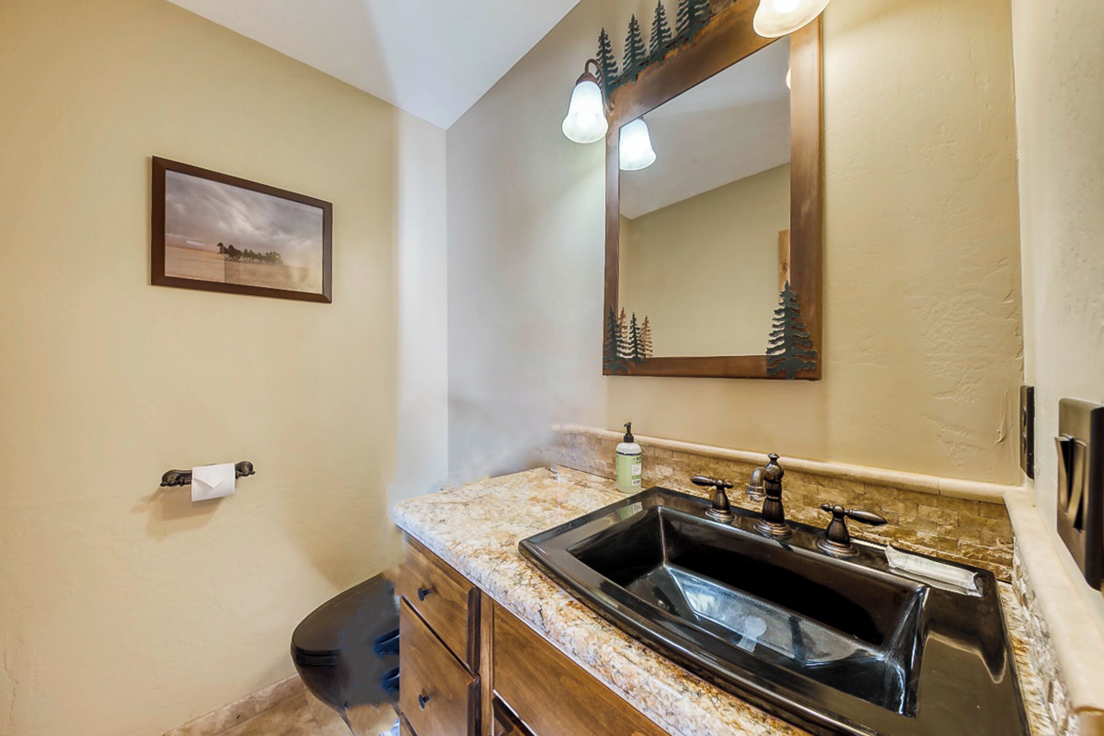 A bathroom with a sink, mirror, and a framed picture on the wall.