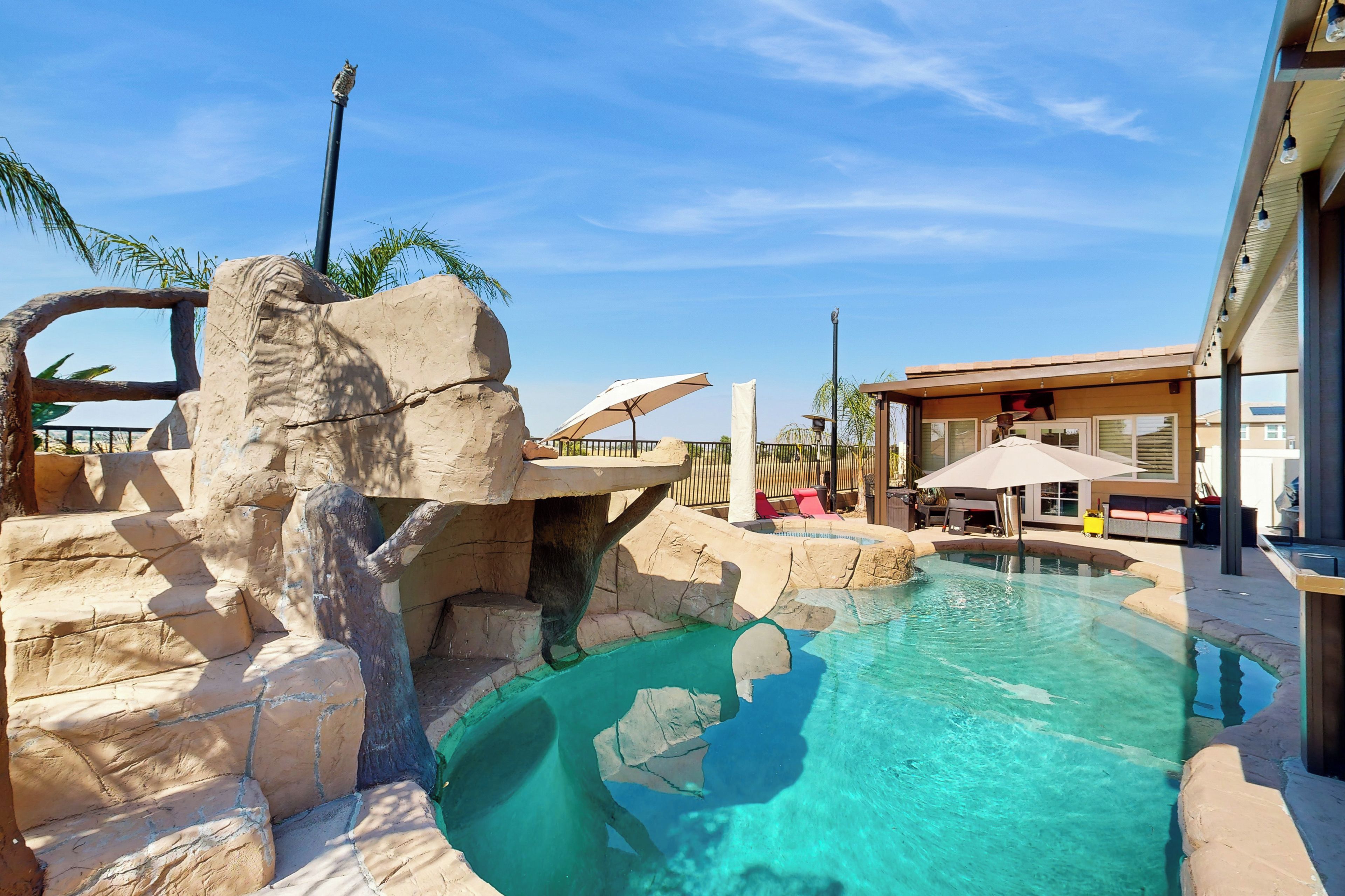 Une piscine entourée d’un paysage rocheux et un bâtiment doté d’un espace extérieur aménagé pour s’asseoir.