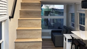 A modern kitchen with a wooden staircase, a dining area, and large windows offering a view of the outdoors. - Outdoor Oasis w/ Pool & Hot Tub: Perris Getaway (Perris)