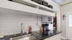A modern kitchen with a black countertop, stainless steel sink, white cabinets, a microwave, and a fire extinguisher. - Outdoor Oasis w/ Pool & Hot Tub: Perris Getaway (Perris)