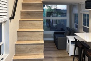 Una cocina moderna con escalera de madera, zona de comedor y grandes ventanales con vistas al exterior.