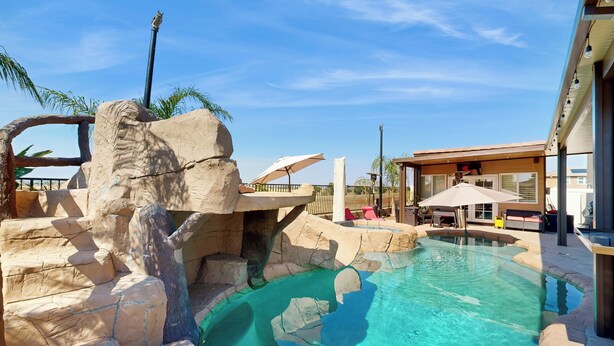 A swimming pool with a rocky landscape and a building with outdoor seating. - Outdoor Oasis w/ Pool & Hot Tub: Perris Getaway (Perris)