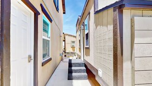A narrow alleyway between two buildings with a set of concrete steps leading to a door. - Outdoor Oasis w/ Pool & Hot Tub: Perris Getaway (Perris)