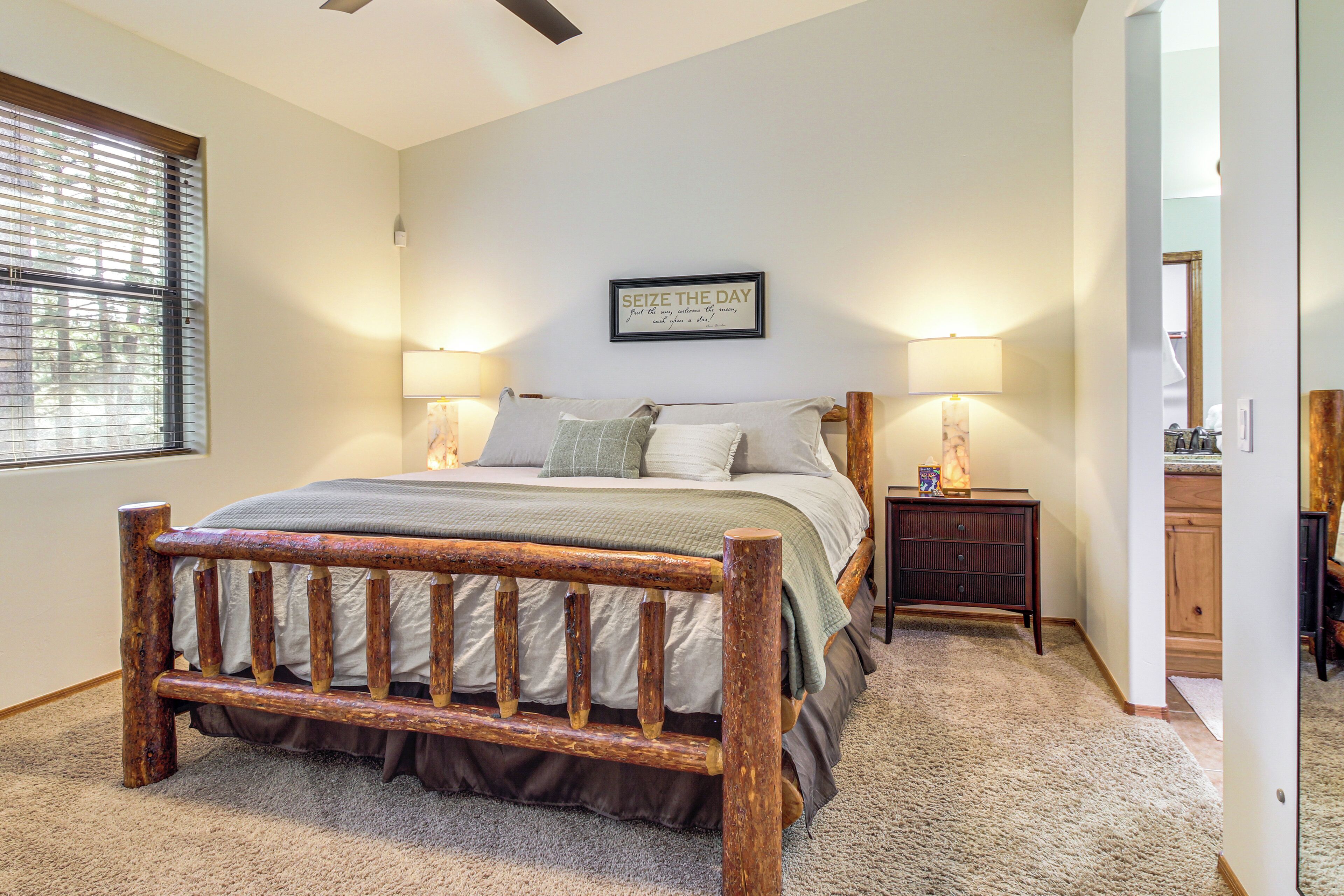 A bedroom with a wooden bed frame, two bedside lamps, a nightstand, and a framed quote on the wall.