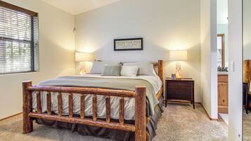 A bedroom with a wooden bed frame, two bedside lamps, a nightstand, and a framed quote on the wall.