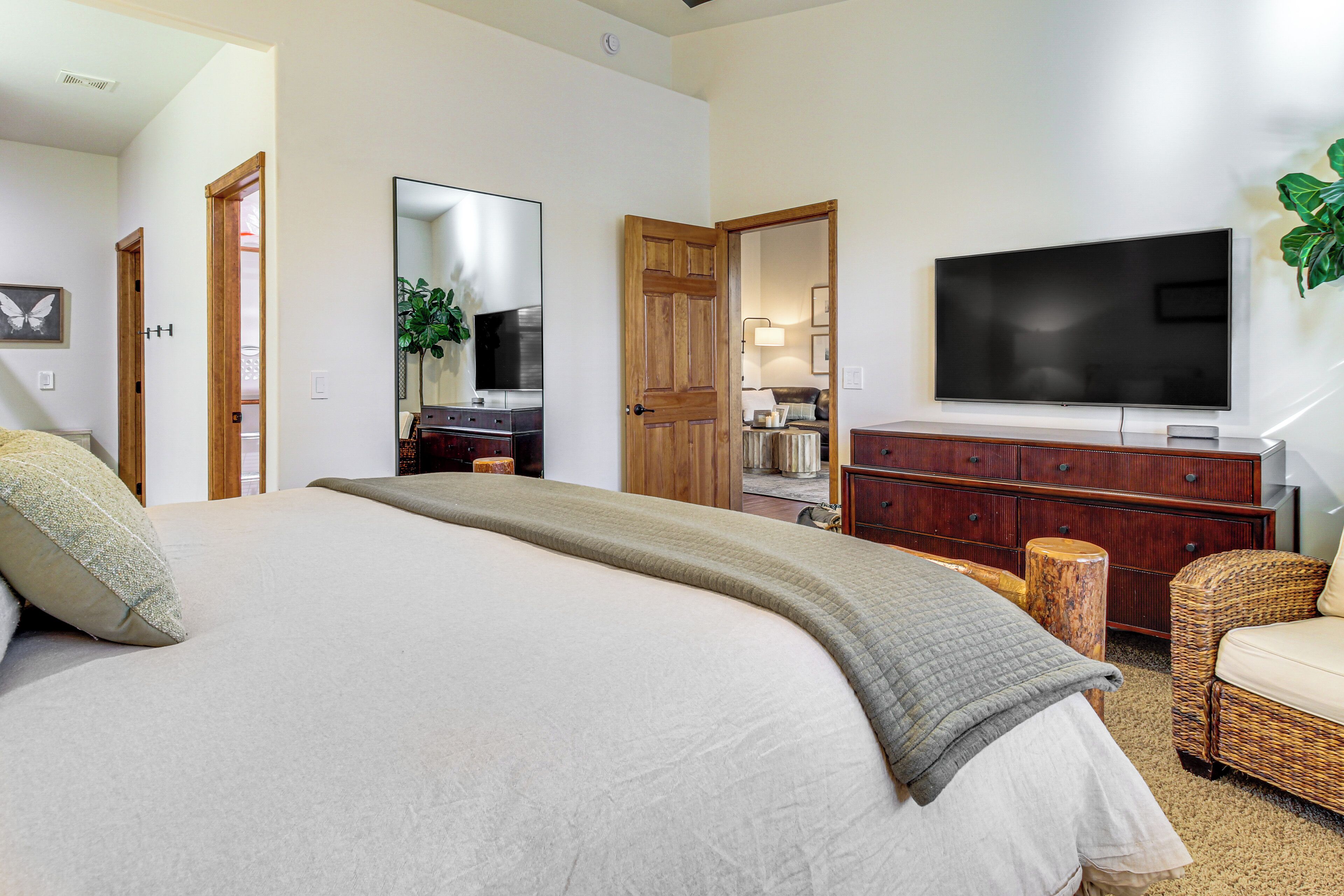A bedroom with a large bed, a dresser, a television, and a mirror.
